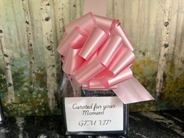 Gift with a pink bow and a card reading 'Curated for your Moment GEM VIP' against a natural background.