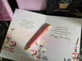 Open birthday card with floral design, pen, and pink envelope on a textured surface