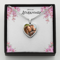 Heart-shaped necklace with a photo of a couple in a decorative box with floral design and 'Life is an Adventure' text.